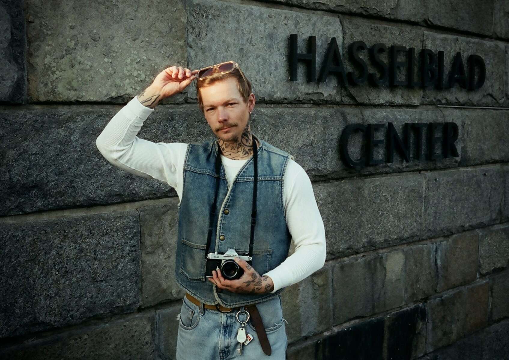 Analog bild på man med jeansväst och analog kamera